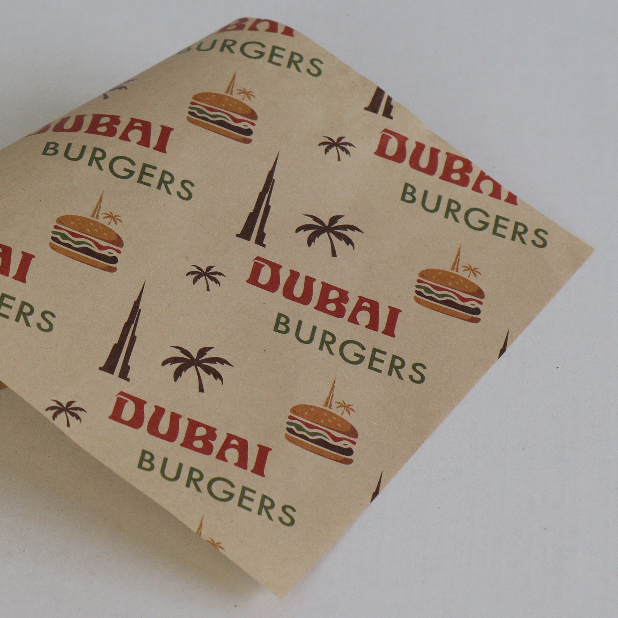 Kraft paper with 'Dubai Burgers' branding and graphics on a white background